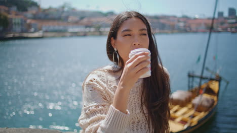 girl drinking tea sunlight marine town closeup. woman tourist enjoying beverage