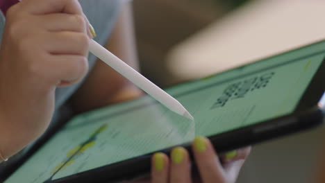 primer plano de una mujer de negocios estudiante usando una tableta digital navegando por un proyecto de investigación de marketing en la pantalla viendo documentos corporativos en línea en la oficina manos lápiz
