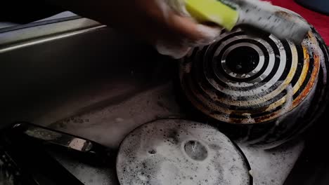 person cleaning pans in the sink by hand with a scouring pad