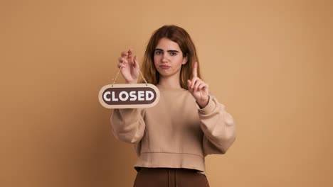 young woman standing with closed sign near wall