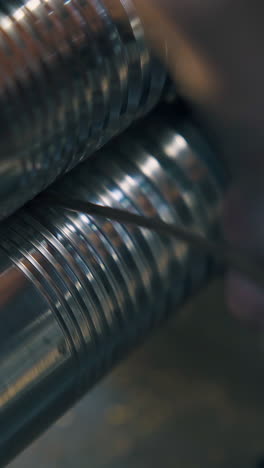 cu: professional goldsmith forge-rolls gold metal rod with mechanical forge-roller on table at workplace close view