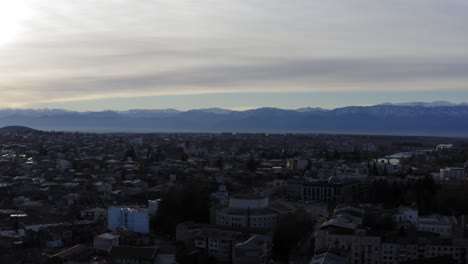 aerial flying over kutaisi city with snowy mountains and river georgia country