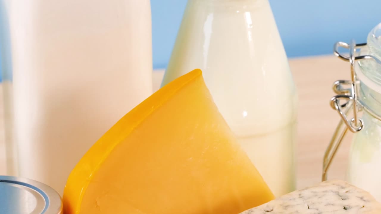 A variety of cheeses and milk bottles arranged against a blue background, highlighting texture and freshness.