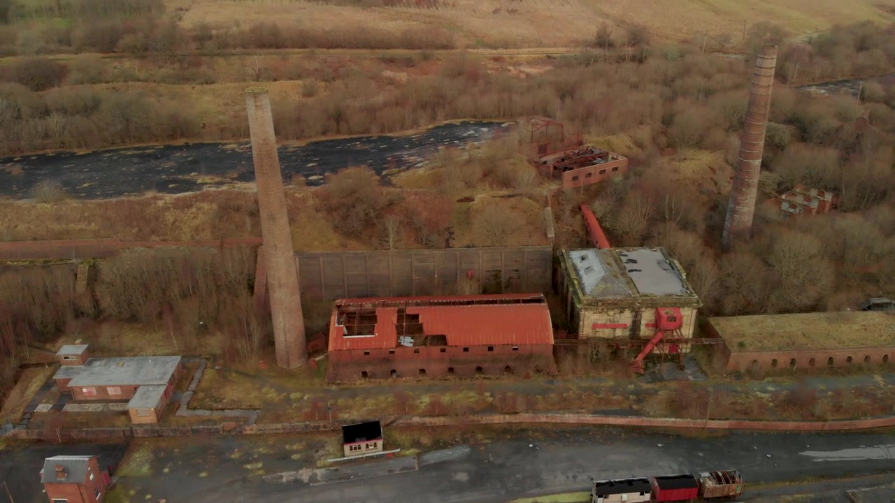 Un'inquadratura dal basso verso l'alto rivela i camini di Dunaskin e gli edifici di fabbriche in rovina, Ayrshire