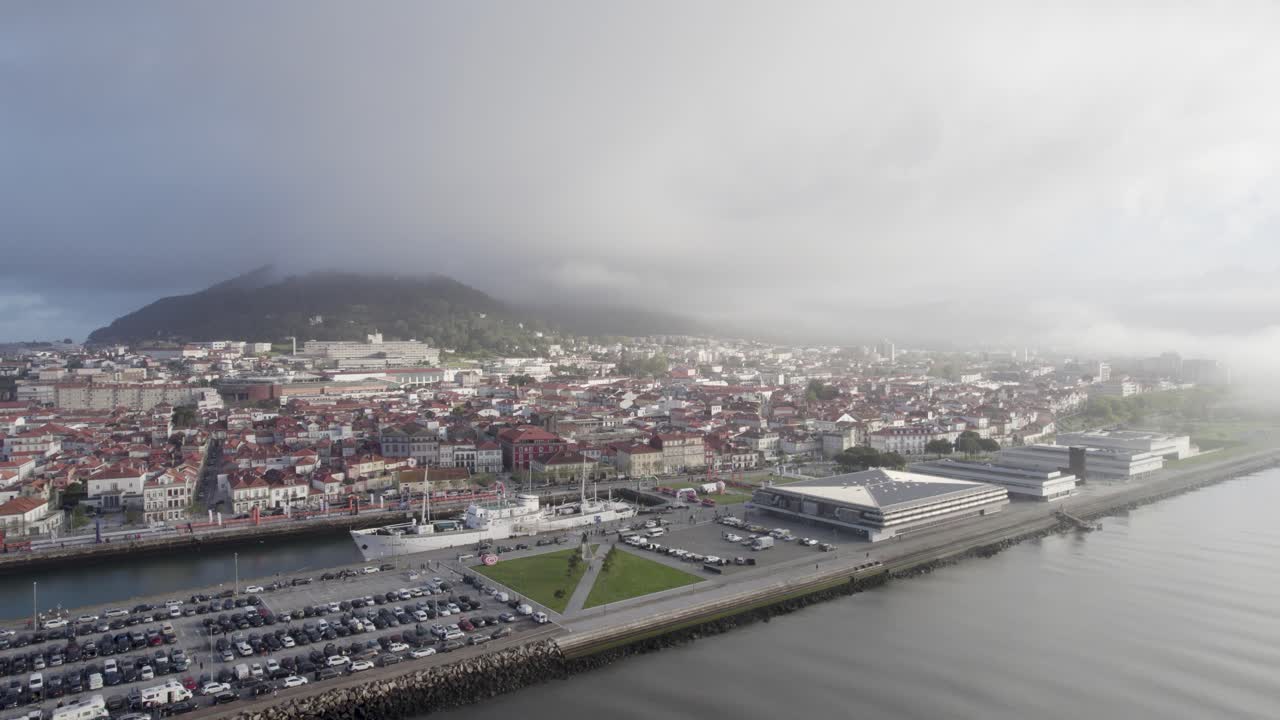 Aerial of Viana do Castelo, Portugal, with fog covering the hills and city by the Atlantic Ocean