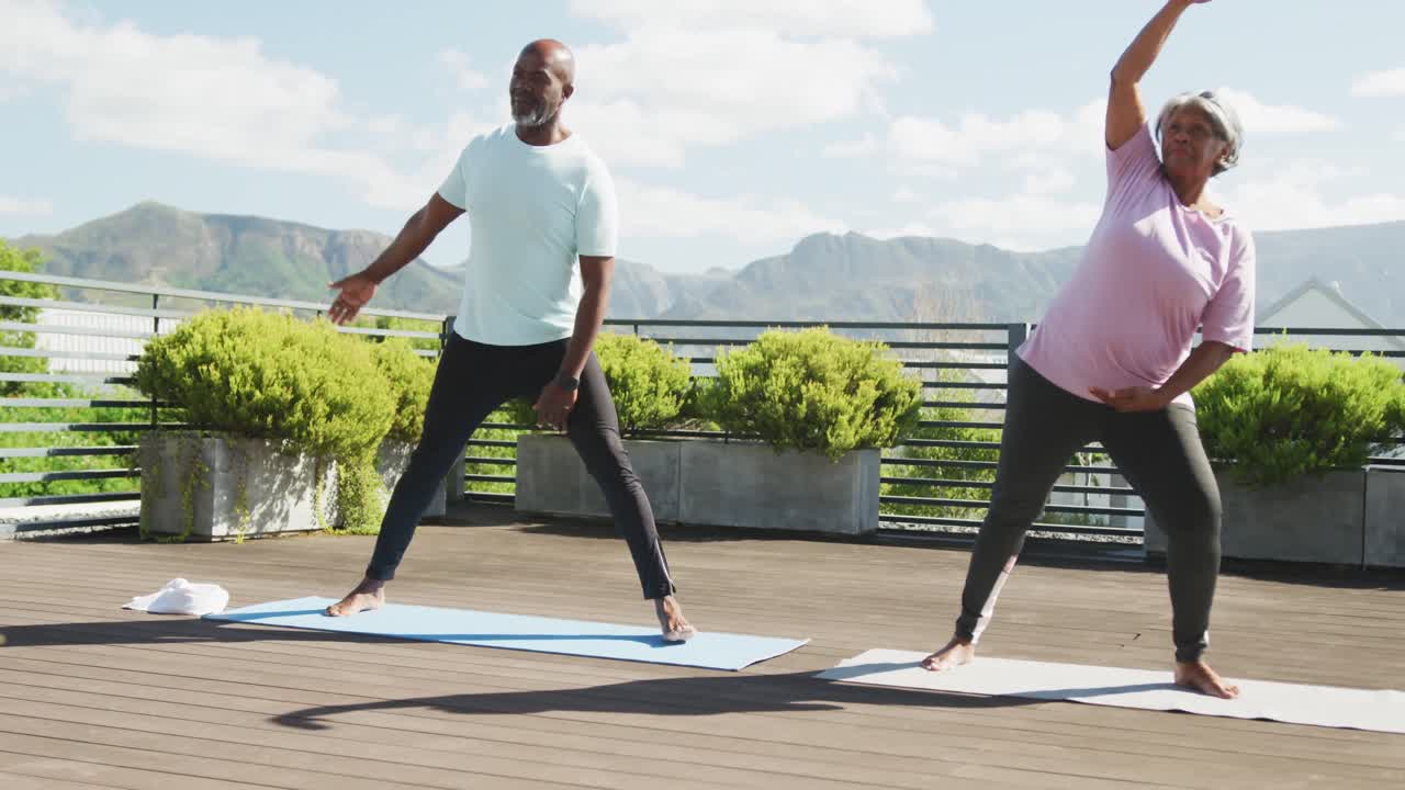 Video of happy african american couple exercise on the terrace