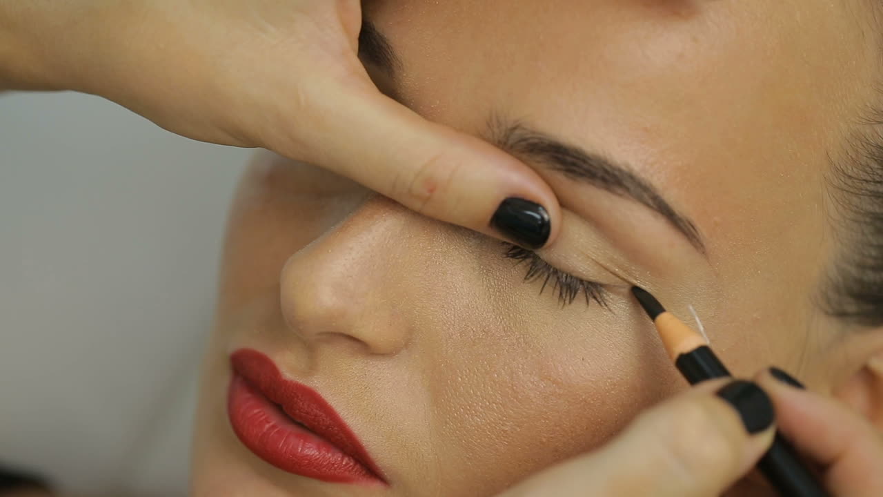 Woman Lying On Couch At Beauty Salon. Cosmetologist making eyeliner permanent make up