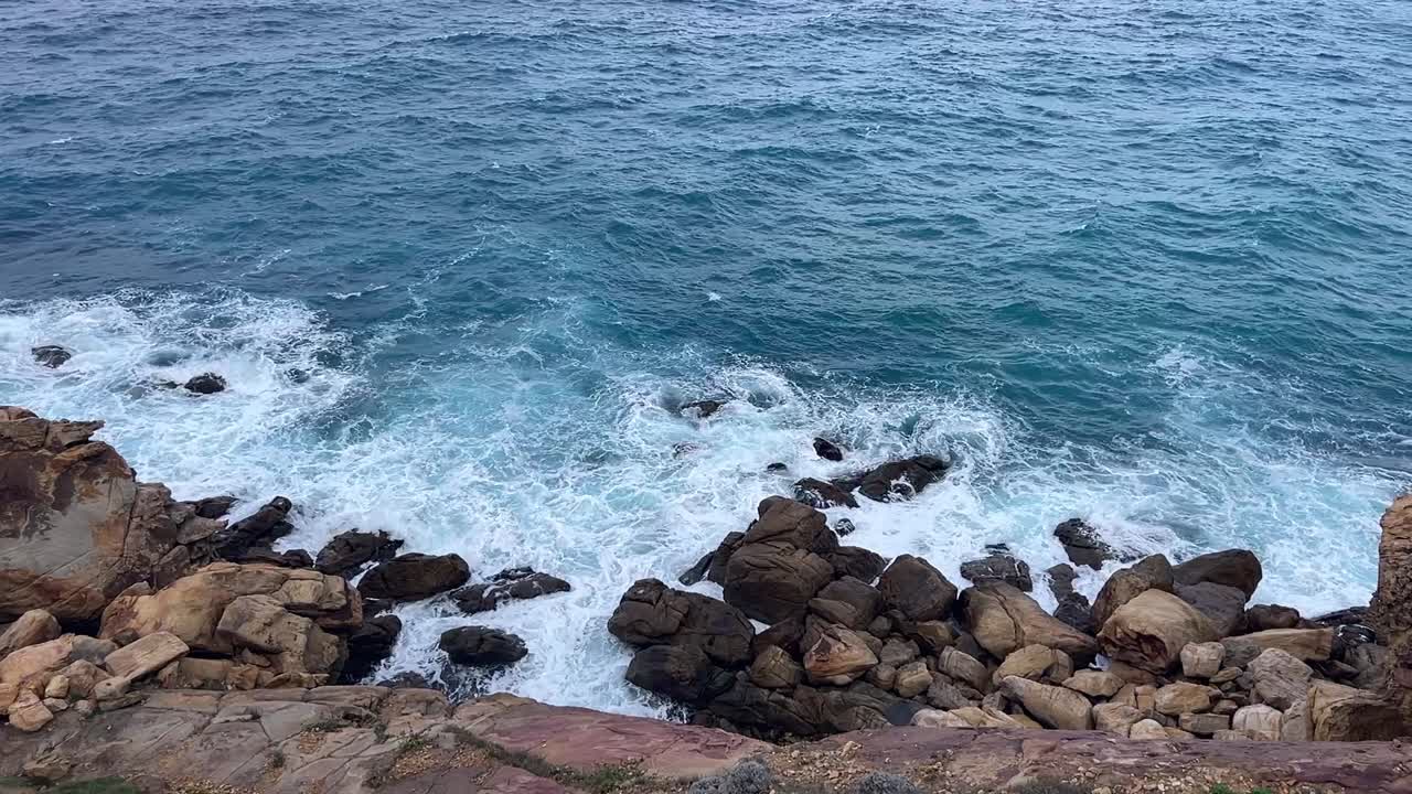 vista en cámara lenta de las olas que se rompen en la costa rocosa