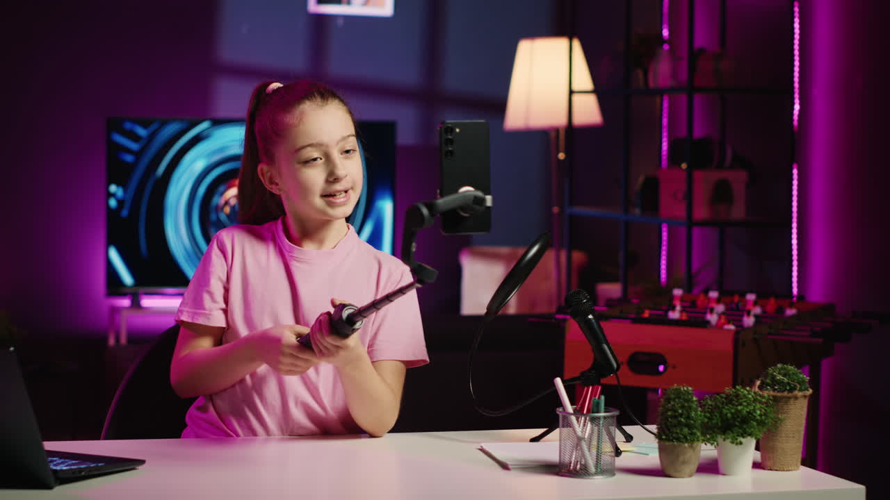 온라인 채널을 위해 셀피 스틱에 인 드폰으로 비디오를 촬영하는 어린이, 시청자와 대화하는