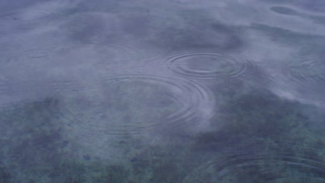 rain drops falling on calm lake