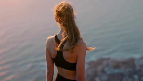 Mujer-Sana-En-La-Cima-De-La-Montaña-Mirando-La-Vista-Del-Océano-Al-Atardecer-Chica-Parada-En-El-Borde-Del-Acantilado-Disfrutando-De-La-Libertad-Contemplando-El-Viaje-A-La-Cumbre