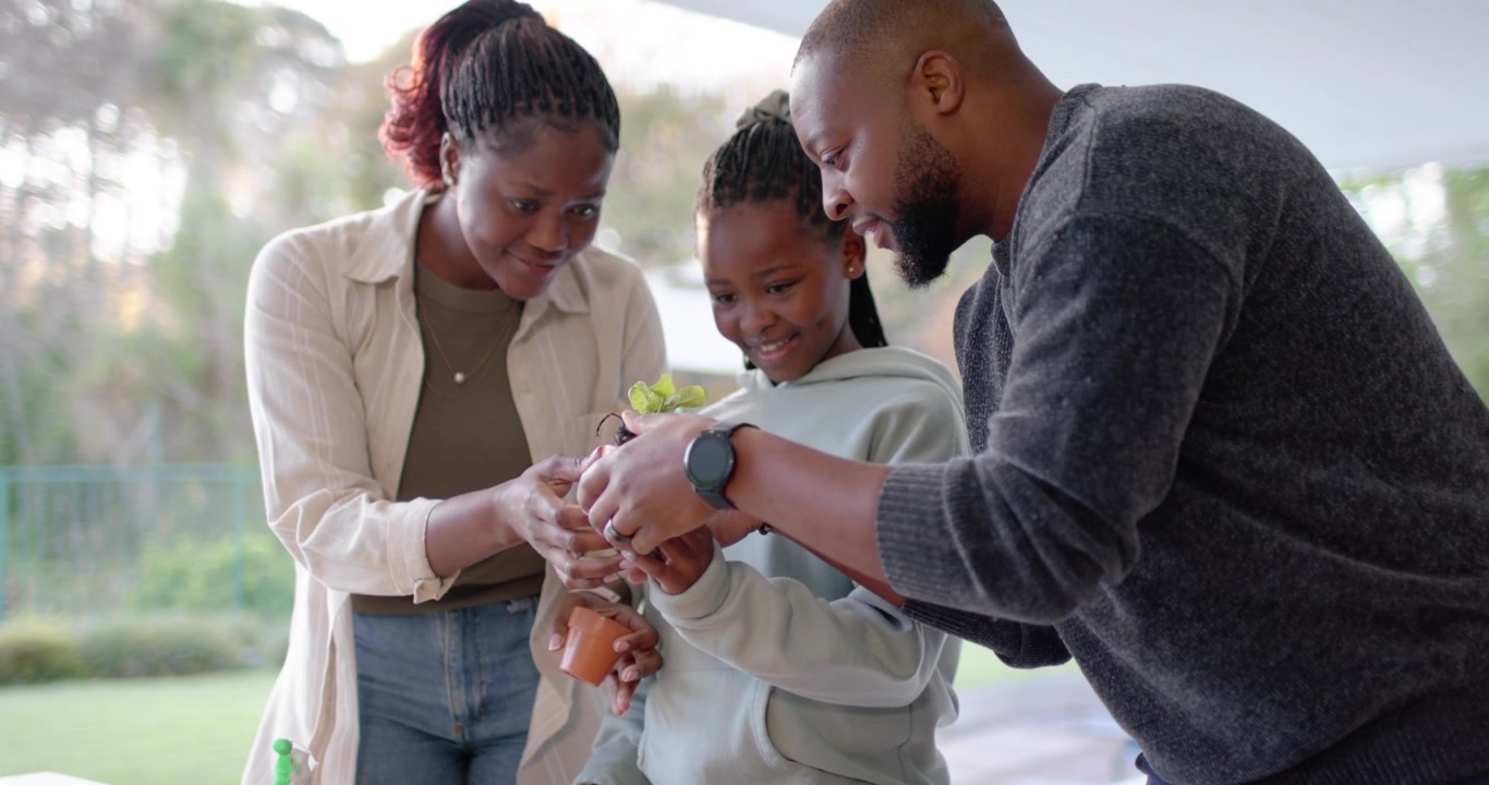 Mani tese, famiglia afroamericana che insegna alla figlia a piantare piantine sul portico usando vasi.