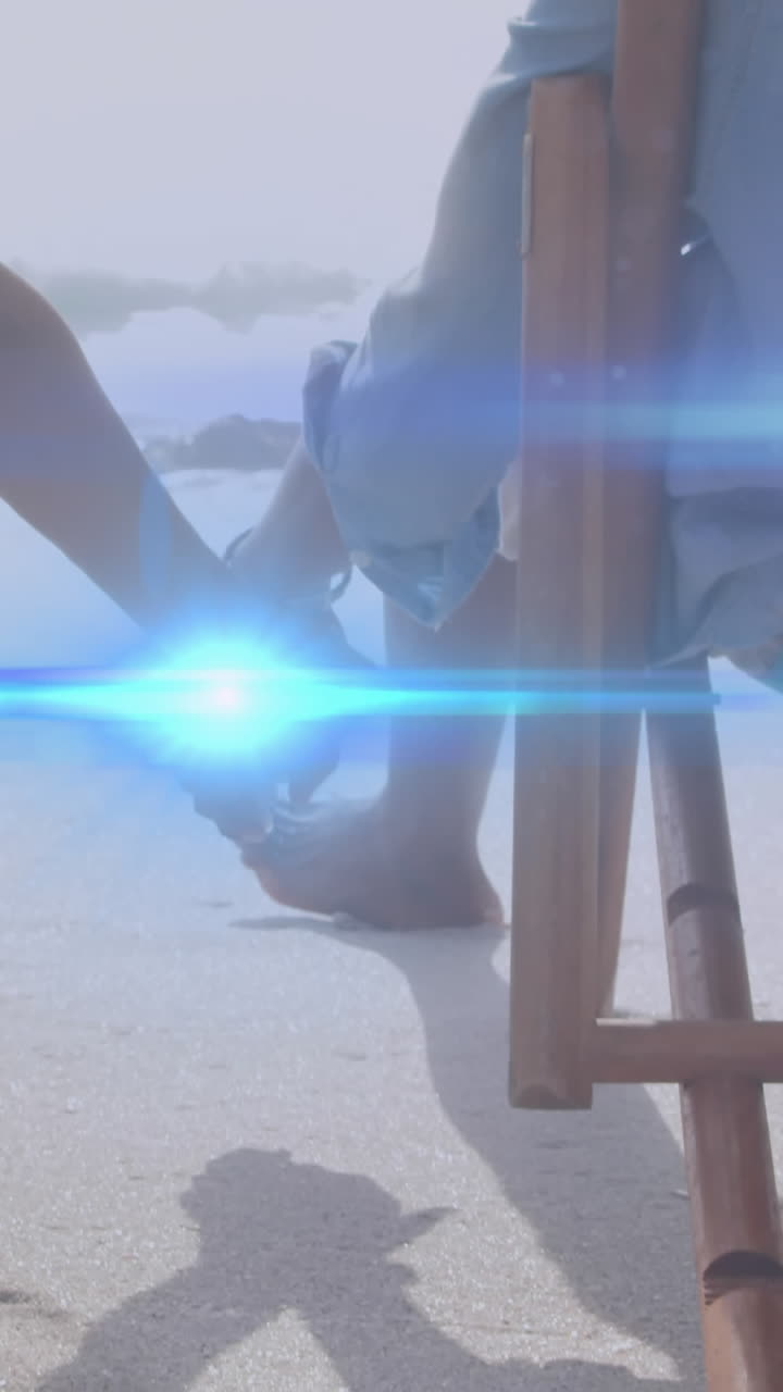 animación de la luz moviéndose sobre una pareja mayor en sillas de playa tomados de la mano