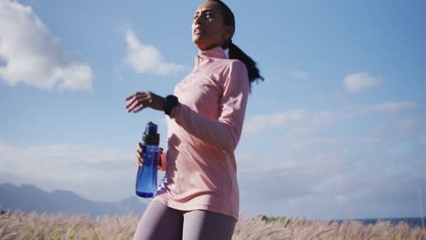 Mujer-De-Raza-Mixta-Haciendo-Ejercicio-Corriendo-En-El-Campo-Parando-A-Beber