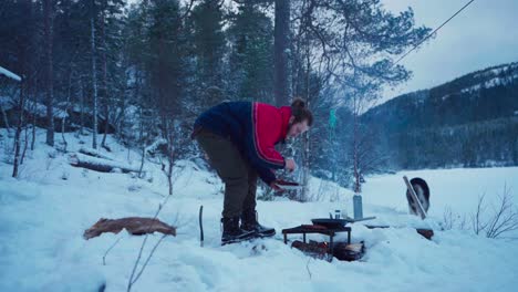 Hombre-Con-Soporte-De-Parrilla-De-Metal-Está-Cocinando-Fuera-Del-Paisaje-Invernal