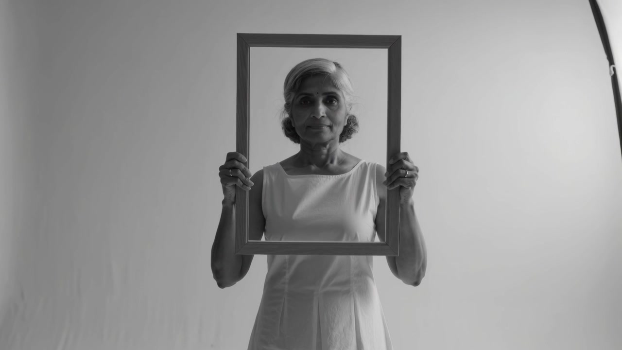 Rispondendo a un segnale, modella indiana anziana che incornicia il viso con una cornice quadrata in studio.