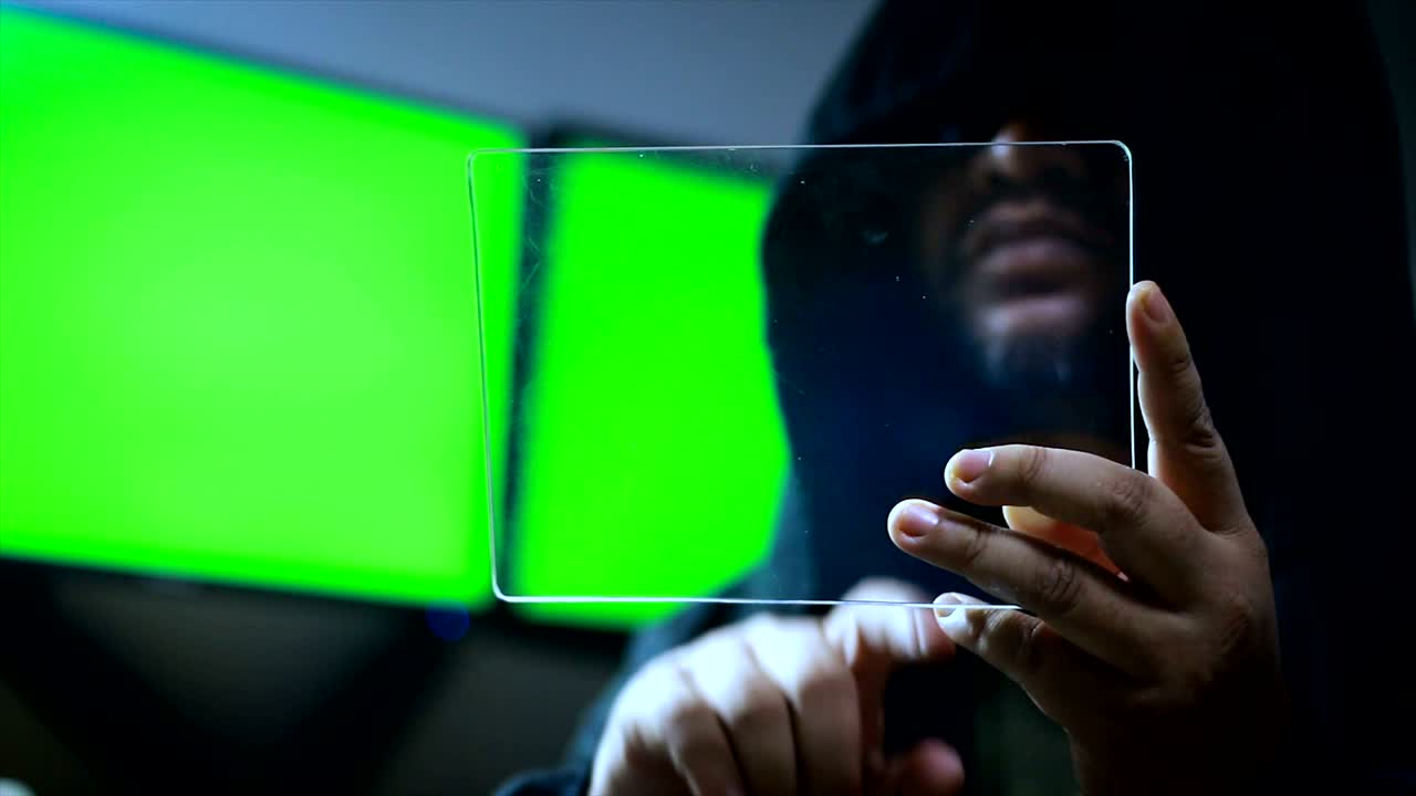 utilizzando un tablet trasparente con uno schermo verde sullo sfondo del monitor hacker