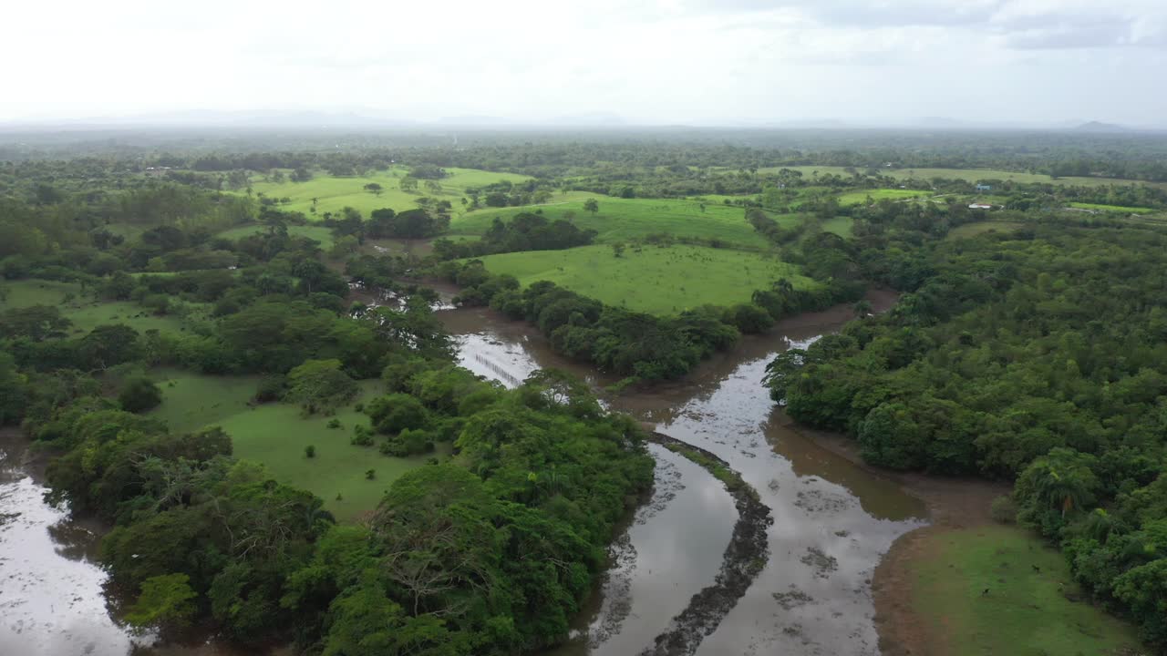 toma aerea en areas verdes sobre el rio ozama con aguas pardas por las lluvias