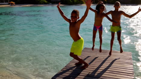 children jumping from dock into water