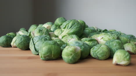 close up slow motion push in to heap of raw brussels sprouts on wooden tabletop