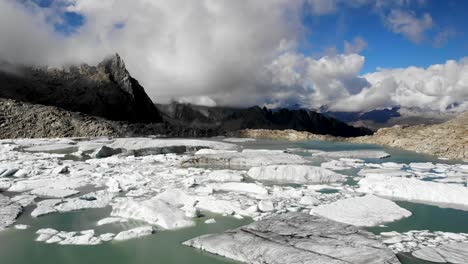 Aerial-flyover-above-a-glacier-lake-full-of-melted-icebergs-in-remote-parts-of-the-Swiss-Alps-on-a-sunny-day