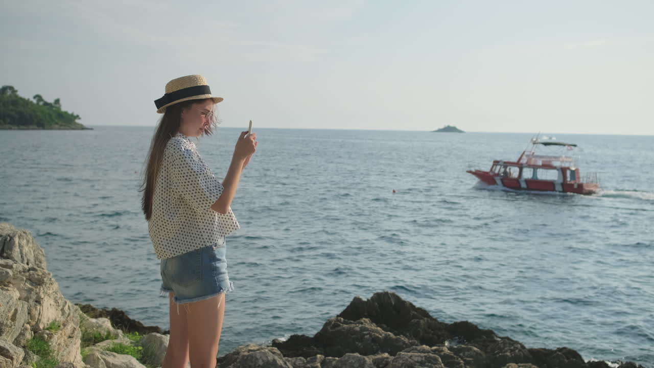 mujer tomando una foto de un barco en la playa