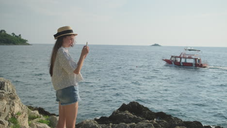 mujer tomando una foto de un barco en la playa