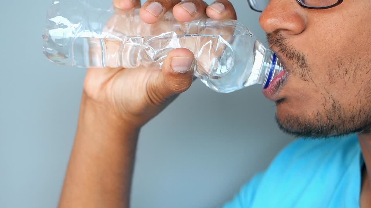 Person Drinking Water from Plastic Bottle