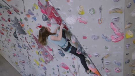 close up: young girl loops her belay rope into a carabiner while lead climbing