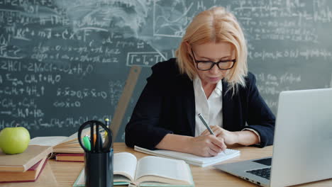teacher working at a desk in a classroom