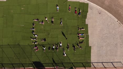 gruppo di bambini sdraiati sul tappeto verde all'aperto durante la lezione di educazione fisica