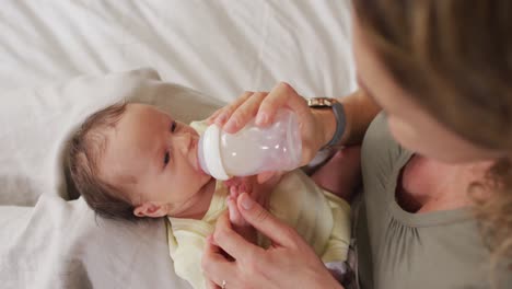 Video-Einer-Glücklichen-Kaukasischen-Mutter,-Die-Ihr-Neugeborenes-Baby-Mit-Der-Flasche-Auf-Dem-Bett-Füttert