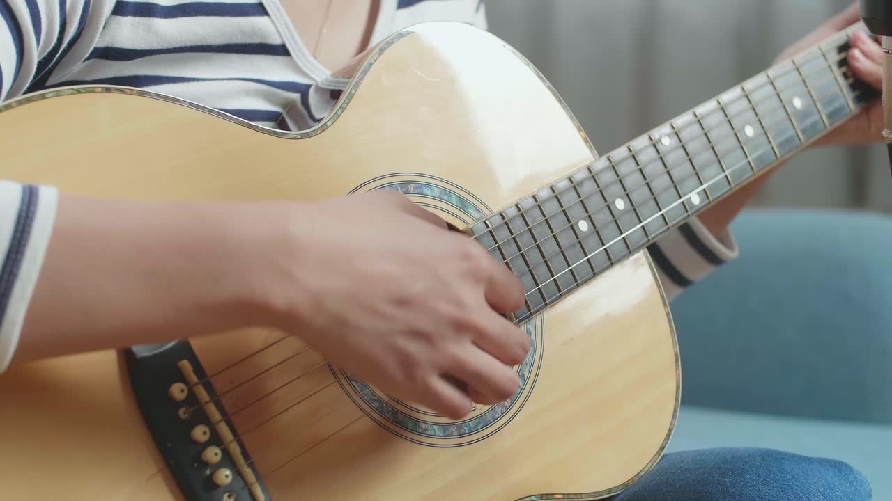 cerca de las manos de la mujer tocando la guitarra en casa