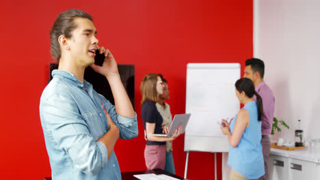 Male-executive-talking-on-mobile-phone-in-the-conference-room