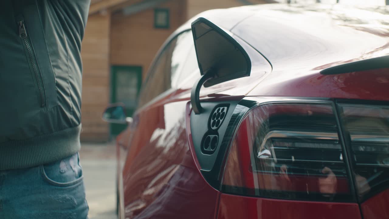 Man pulls out the charging cable from the electric car