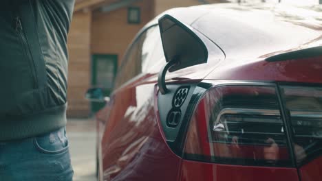 man pulls out the charging cable from the electric car