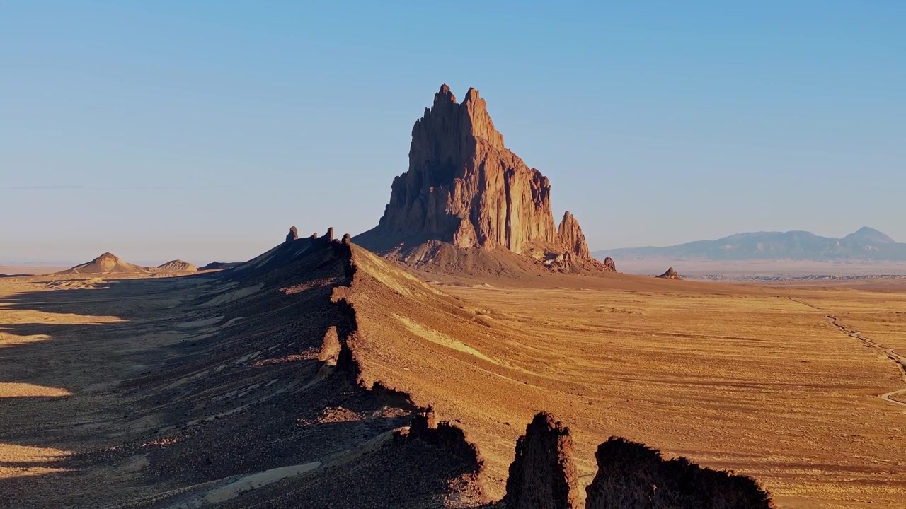 Chuyển động mượt mà trên không qua những rặng núi sa mạc sắc nhọn với Shiprock sừng sững trên đường chân trời xa xăm.