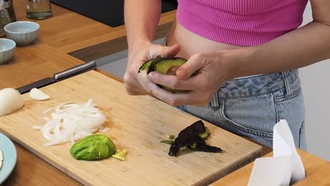 woman peeling and cutting avocado