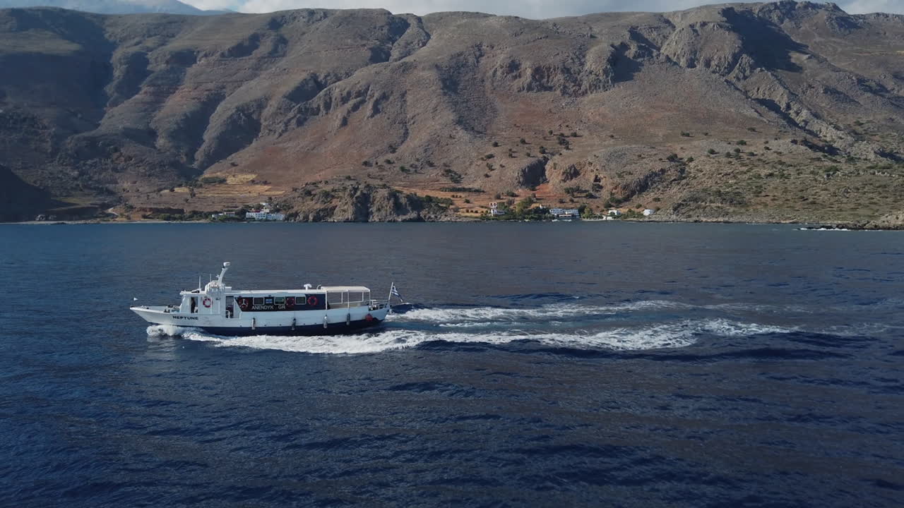 lanzamiento de barcos en los mares del sur de creta frente a un paisaje montañoso y volcánico