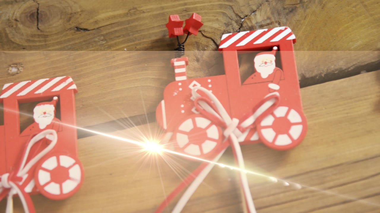 Animation of light moving over christmas train decorations on wooden surface