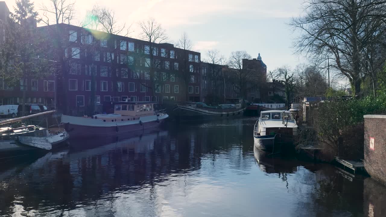 Friedlicher Stadtkanal mit Hausbooten und Gebäudespiegelungen