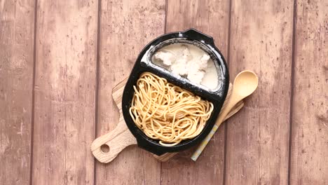espagueti con salsa de crema de pollo en un recipiente desechable
