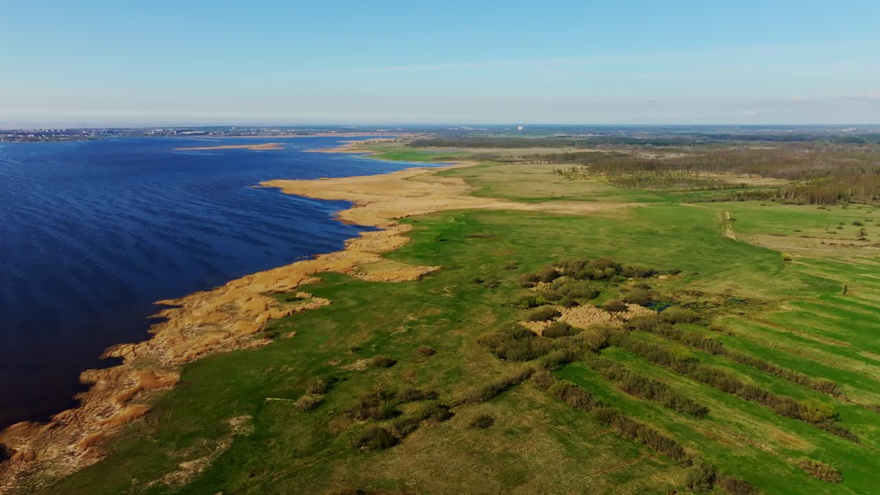 Vista aérea tranquila de la costa de Liepaja, Letonia, con campos y un lago en calma