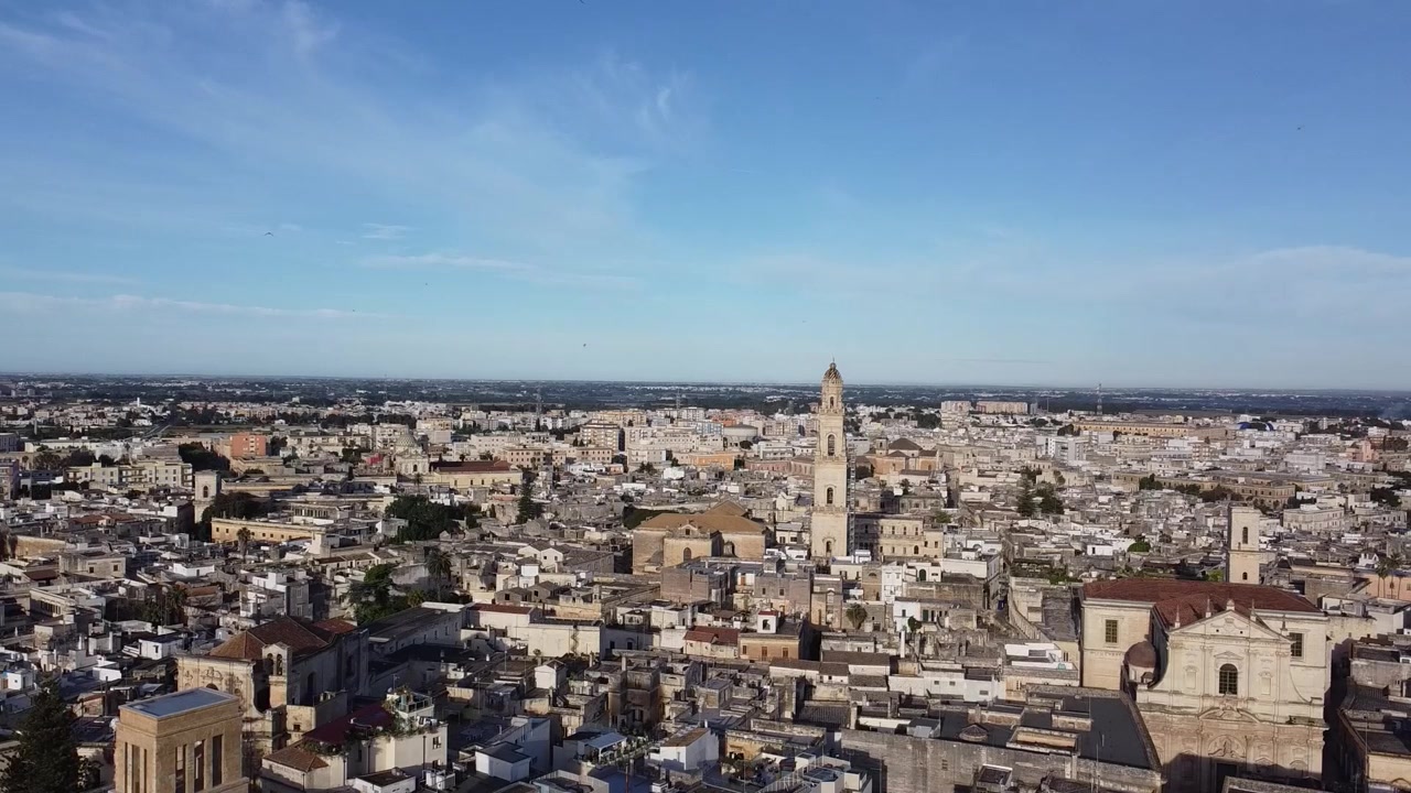 Panorama aereo con drone di edifici bianchi e color crema che circondano il campanile del Duomo di Lecce, ampio paesaggio urbano che mette in mostra l'architettura storica a Lecce, Puglia, Italia.