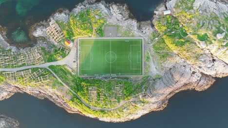 high-altitude upward aerial view over the famous henningsvaer football field on the lofoten islands during sunset