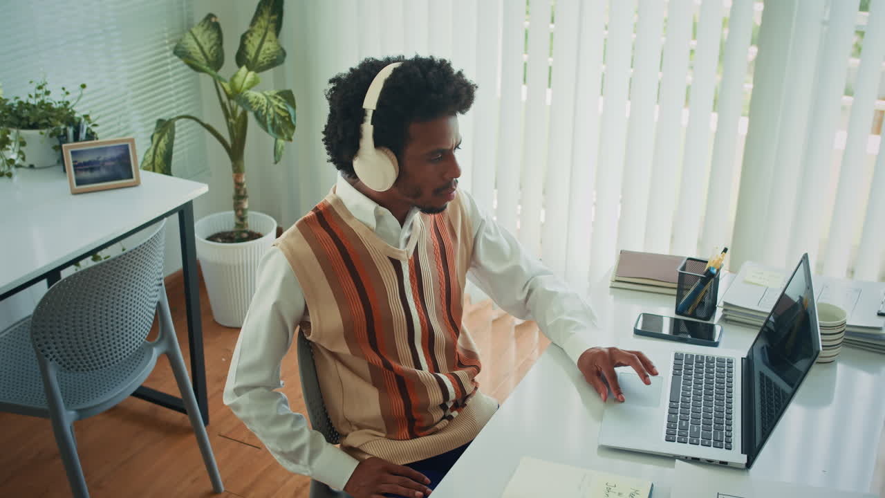 African American Employee in Headphones Working at Office Desk