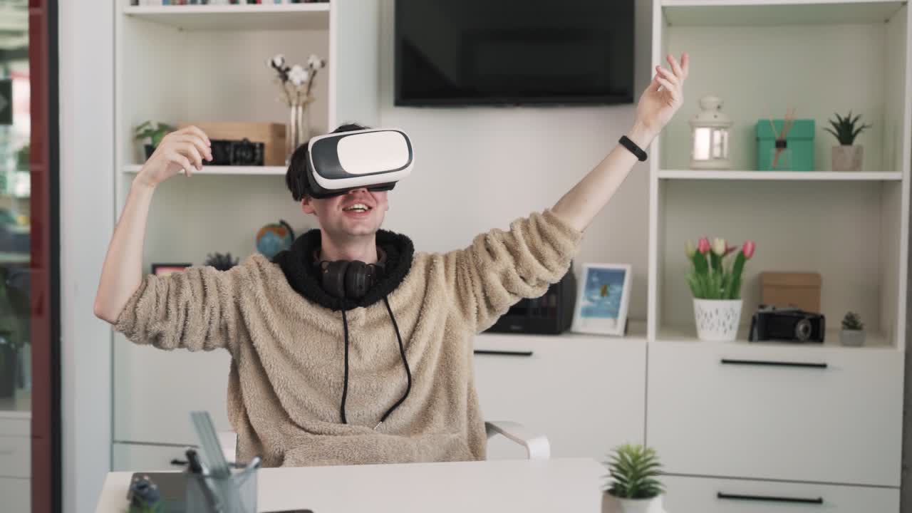 The boy is sitting at the table wearing VR goggles. He is both bewildered and joyful, making hand gestures. The boy in VR goggles flies as if he were Superman.