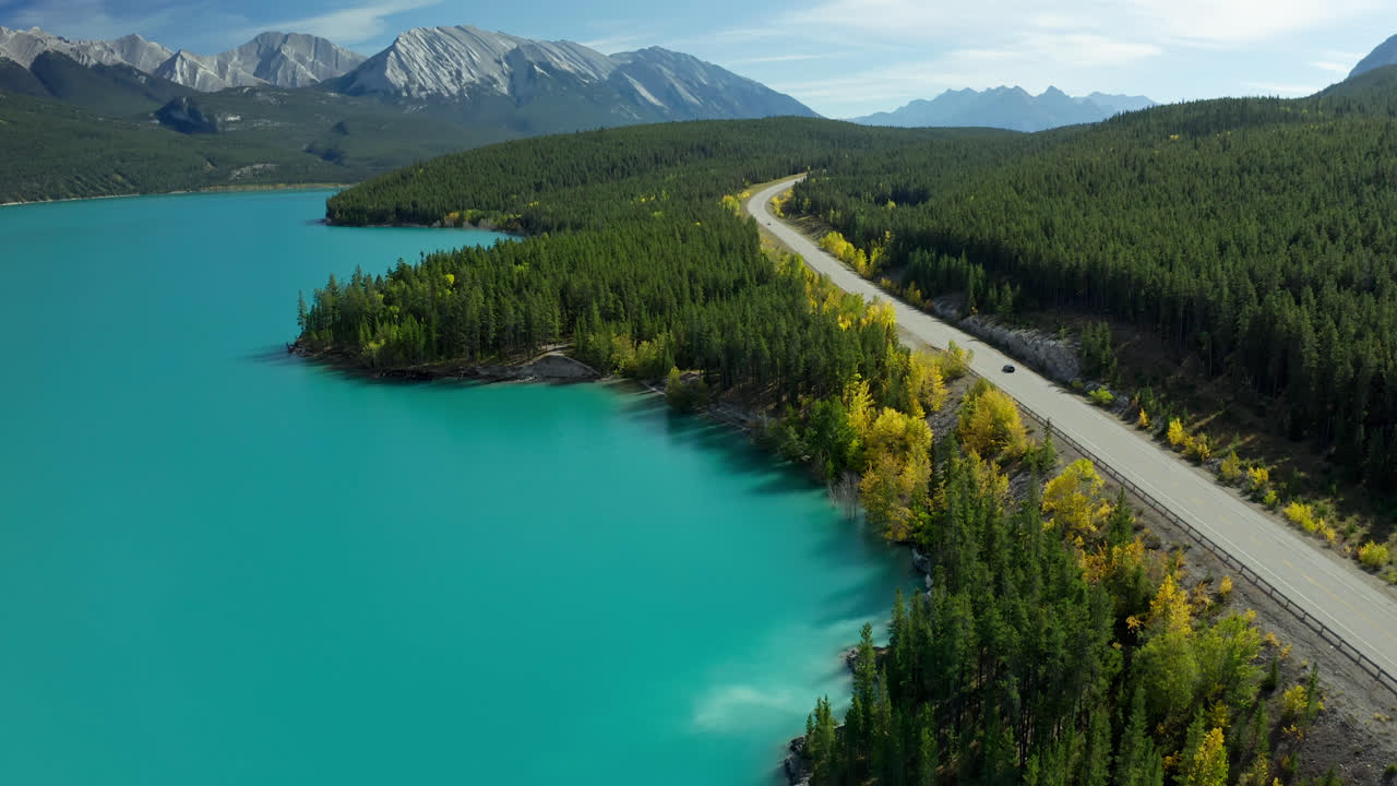 Explore the breathtaking turquoise waters of Abraham's Lake in Alberta, Canada, with its surrounding lush forests and vibrant autumn colors capturing nature's beauty.