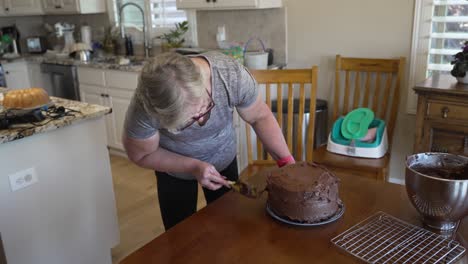 Mujer-Mayor-Ama-De-Casa-Glaseado-De-Un-Pastel---Pastel-De-Chocolate