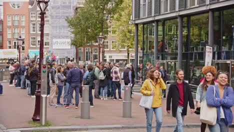 crowd of tourists waiting in line on a street in amsterdam